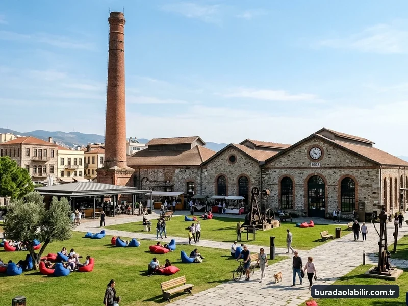 Havagazı Fabrikası Alsancak kırmızı tuğla bacası, endüstriyel taş binaları ve yeşil çim avlusu
