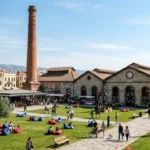 Tarihi Havagazı Fabrikası Alsancak kırmızı tuğla bacası, endüstriyel taş binaları ve yeşil çim avlusu